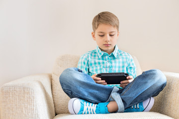 Boy playing hand-held video game on sofa