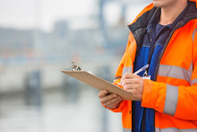 Midsection Of Mid Adult Man Writing On Clipboard In Shipping Yard