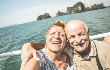 Wall Mural - Happy retired senior couple taking travel selfie around world - Active elderly concept with people having fun together at Phang Nga bay Thailand - Mature people fun lifestyle - Retro contrast filter