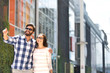 © moodboard - Happy man showing something to woman outside building