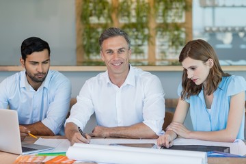 Wall Mural - Business executives discussing reports on wooden table