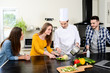 © W PRODUCTION - professional personal chef cook in customer's private kitchen house giving a cooking lesson to young people at home