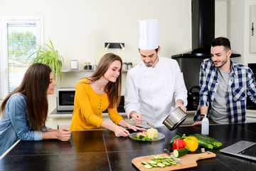 professional personal chef cook in customer's private kitchen house giving a cooking lesson to young people at home