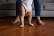 © Lisa Tichané - baby feet learning to walk on a wooden floor with his mother behind him