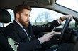 © Drobot Dean - Side view of serious business man using phone at wheel