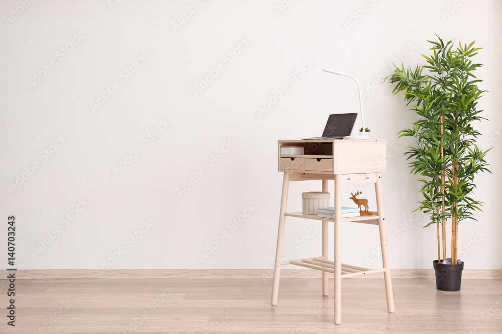 Stand-up desk with laptop near light wall