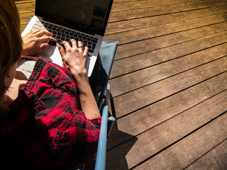 Young woman working while sitting on a patio with her laptop