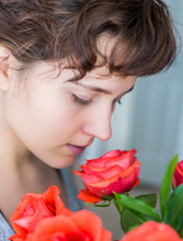 Woman Smelling Red Rose Bouquet In Vase Inside Profile