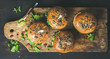 Healthy vegan burger with beetroot and quinoa patty, arugula, avocado sauce, wholegrain bun on rustic wooden board over dark wooden background, top view. Clean eating, detox, vegetarian food concept