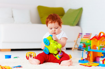 Wall Mural - cute infant redhead baby playing with toys at home