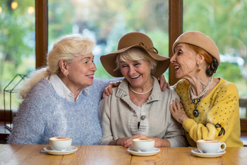 Senior women laughing at table. Happy ladies in cafe. Friendship tested by years.