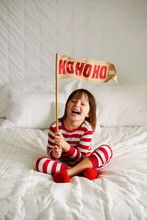 Girl Sitting On Bed Holding A HoHoHo Flag