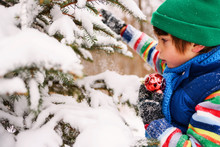 Close Up Of Boy Holding Christmas Decorations In Snow