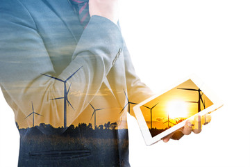 Wall Mural - Double exposure of businessman using tablet with silhouette of wind turbine 