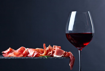 Wall Mural - prosciutto with rosemary and red wine on a black  background