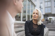 © Maskot - Happy blond businesswoman talking to male colleague in city