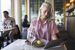 © Maskot - Young blond businesswoman using digital tablet while sitting at table in restaurant