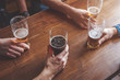 © Karanov images - Hands holding glasses with beer on a table.