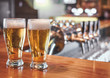 © Karanov images - Two  Glasses of Beer on a bar table. Beer Tap on background