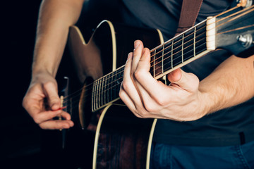 Female hand playing on acoustic guitar. Close-up.