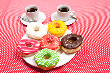 Wall Mural - Colorful Donuts breakfast composition with different color styles of doughnuts and fresh coffee on the side over an aged wooden desk background.