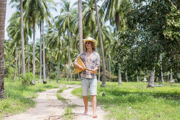 Wall Mural - Man walking and playing music at palm trees background