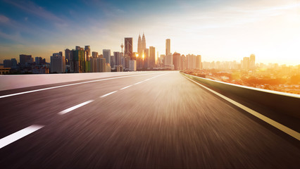 Highway overpass motion blur with city skyline background . Sunset scene .