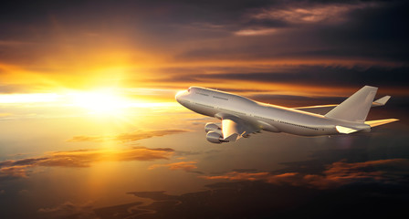 Wall Mural - airplane flying above clouds during sunset
