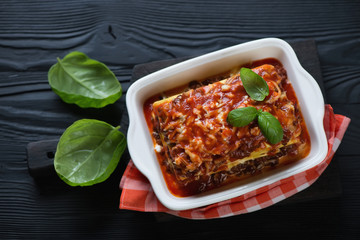 Poster - Lasagna bolognese over black wooden background, top view, studio shot