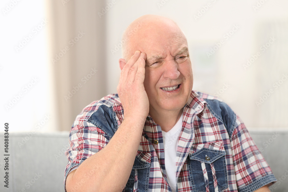 Senior man suffering from headache at home