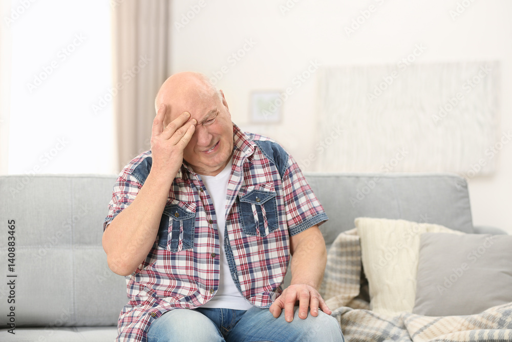 Senior man suffering from headache at home