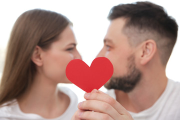 Poster - Happy young couple with red paper heart on white background