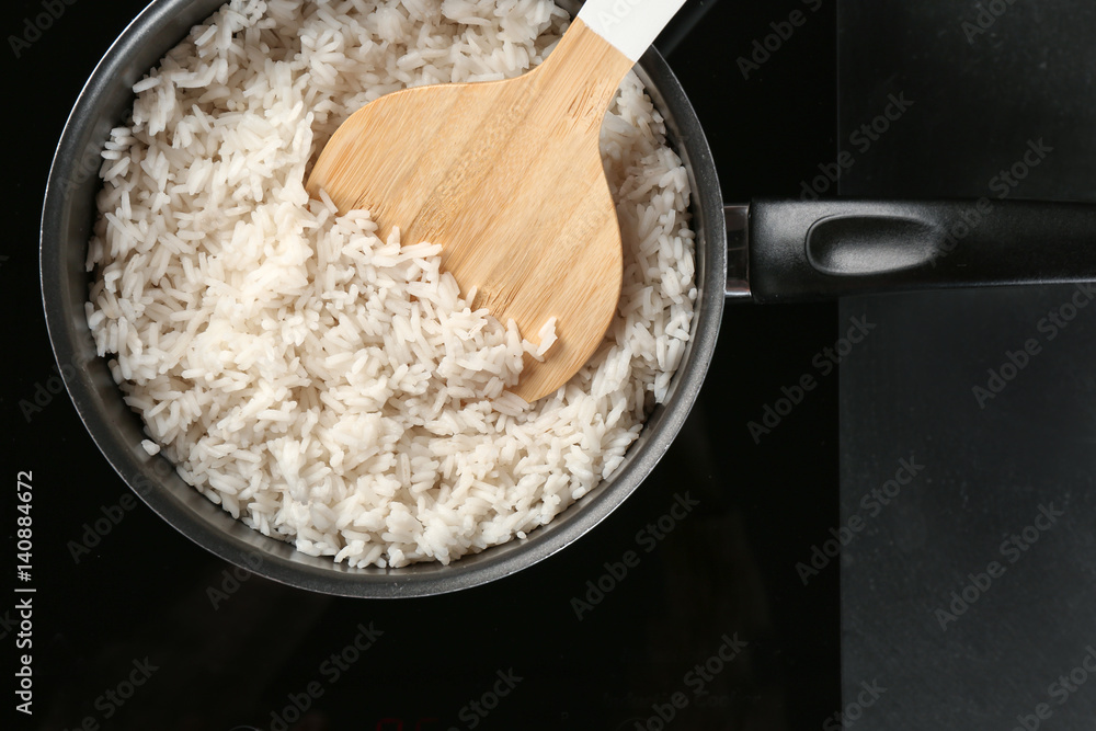 Cooked rice in saucepan with spoon