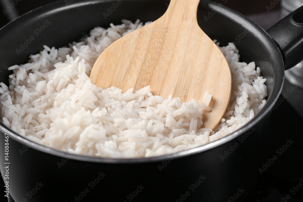 Cooked rice in saucepan with spoon