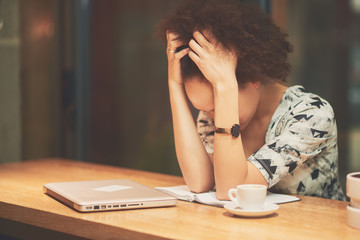 Mixed race woman in coffee shop having headache 