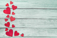 Red Wooden Hearts On The Left Border On A Green Wooden Background With Space For Text
