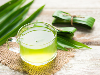 Wall Mural - Glass of pandan juice and pandan leaves on wood background