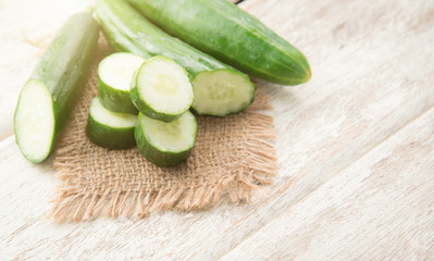 Wall Mural - Cucumber and slices on wood background.