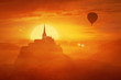 Beautiful sunset landscape over the misty kingdom between the orange hills in the center of nature and the silhouette of a flying air balloon. Fantasy world imaginary view, another reality concept.