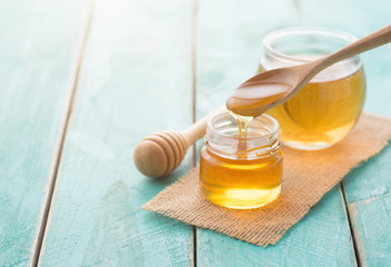 Wall Mural - honey with wooden honey dipper on blue wooden table