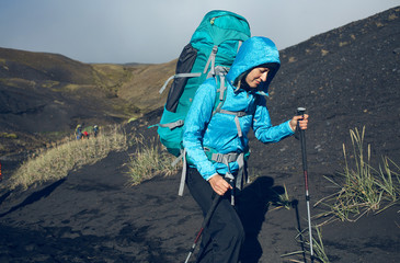 Wall Mural - woman hiker on the trail in the Islandic mountains. Trek in National Park Landmannalaugar, Iceland. valley is covered with volcano asher. Dramatic cloudy sky