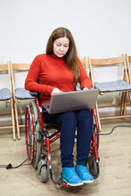 Woman In Invalid Wheel-chair Working With Laptop On Knees, Disabled Person