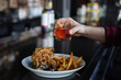© Anna Petrow - Person holding cocktail above counter with bowl of food