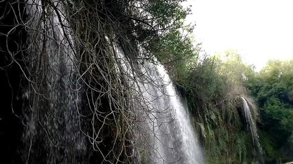 Sticker - View of Kursunlu Waterfall in Antalya, flowing from high, with green trees and plants around.