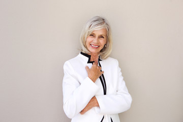 Wall Mural - beautiful older woman smiling and standing by wall