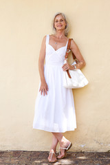 Wall Mural - happy older woman in spring dress standing with purse