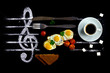 Breakfast concept as notes in music. Fried eggs with tomatoes on a background of a treble clef with a cup of coffee.