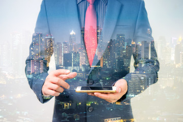 Wall Mural - Businessman using smart phone with city night background 