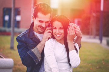 Happy young caucasian couple listening music outdoor in sunset