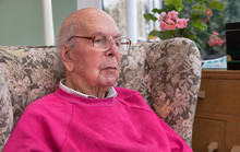 95 Years Old English Man Sitting In Chair In Domestic Environment. Health And Care Concept